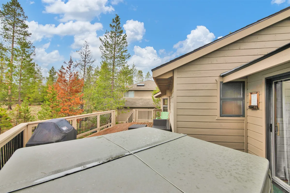 This image depicts a tranquil deck area featuring a private hot tub surrounded by tall trees, creating a serene and secluded atmosphere perfect for relaxation. The deck is spacious, inviting guests to linger outdoors and enjoy the natural setting.