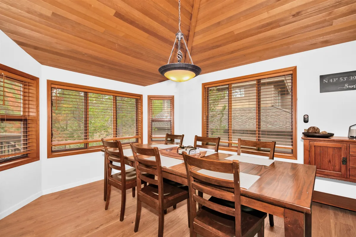 This image focuses on the large wooden dining table set beside expansive windows, with warm natural light streaming in. The space feels welcoming and ideal for shared meals, celebrations, and family gatherings.