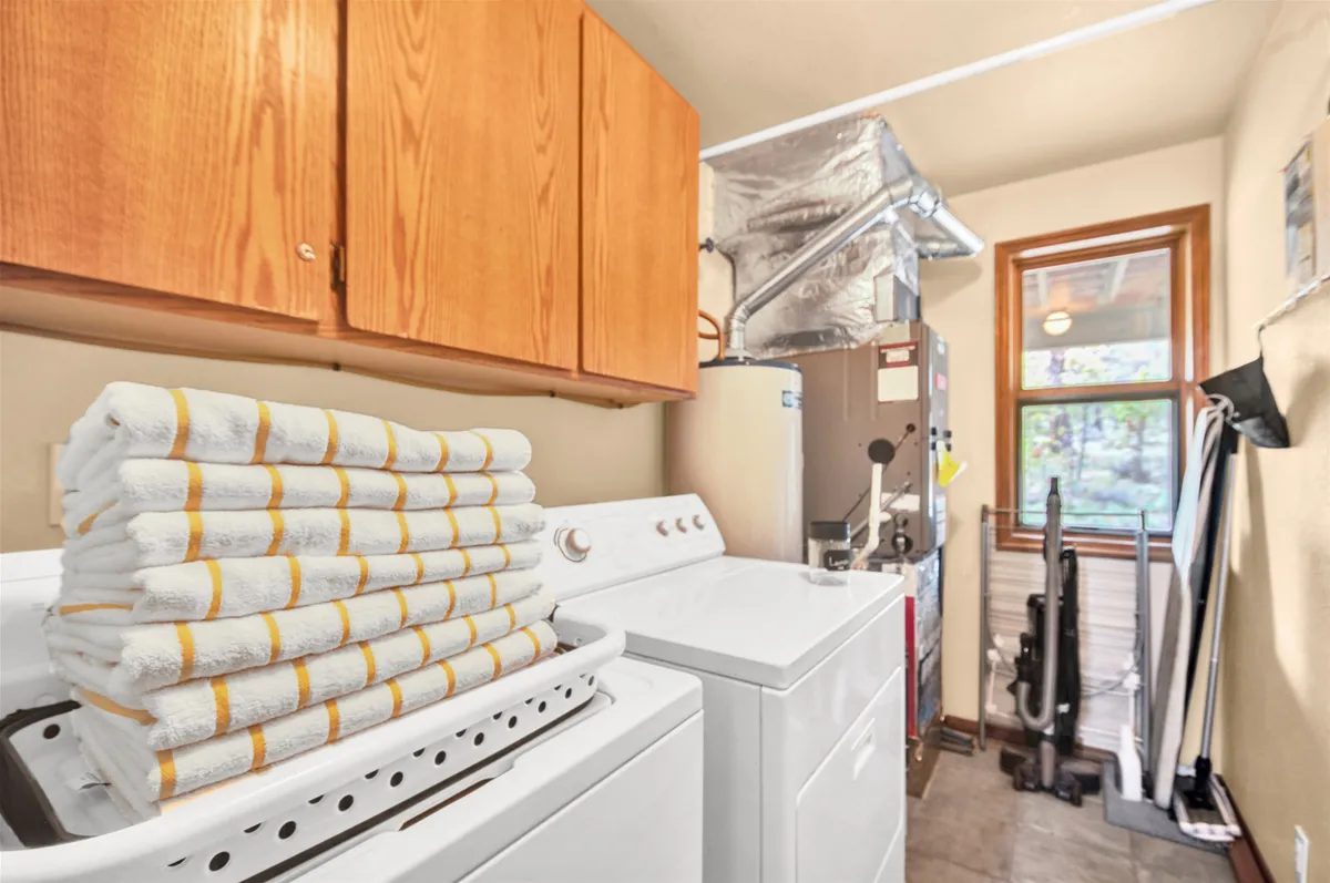 A tidy laundry area with a washing machine, drying machine, and a neatly stacked pile of towels. The space is clean, organized, and practical, highlighting home-like comforts.
