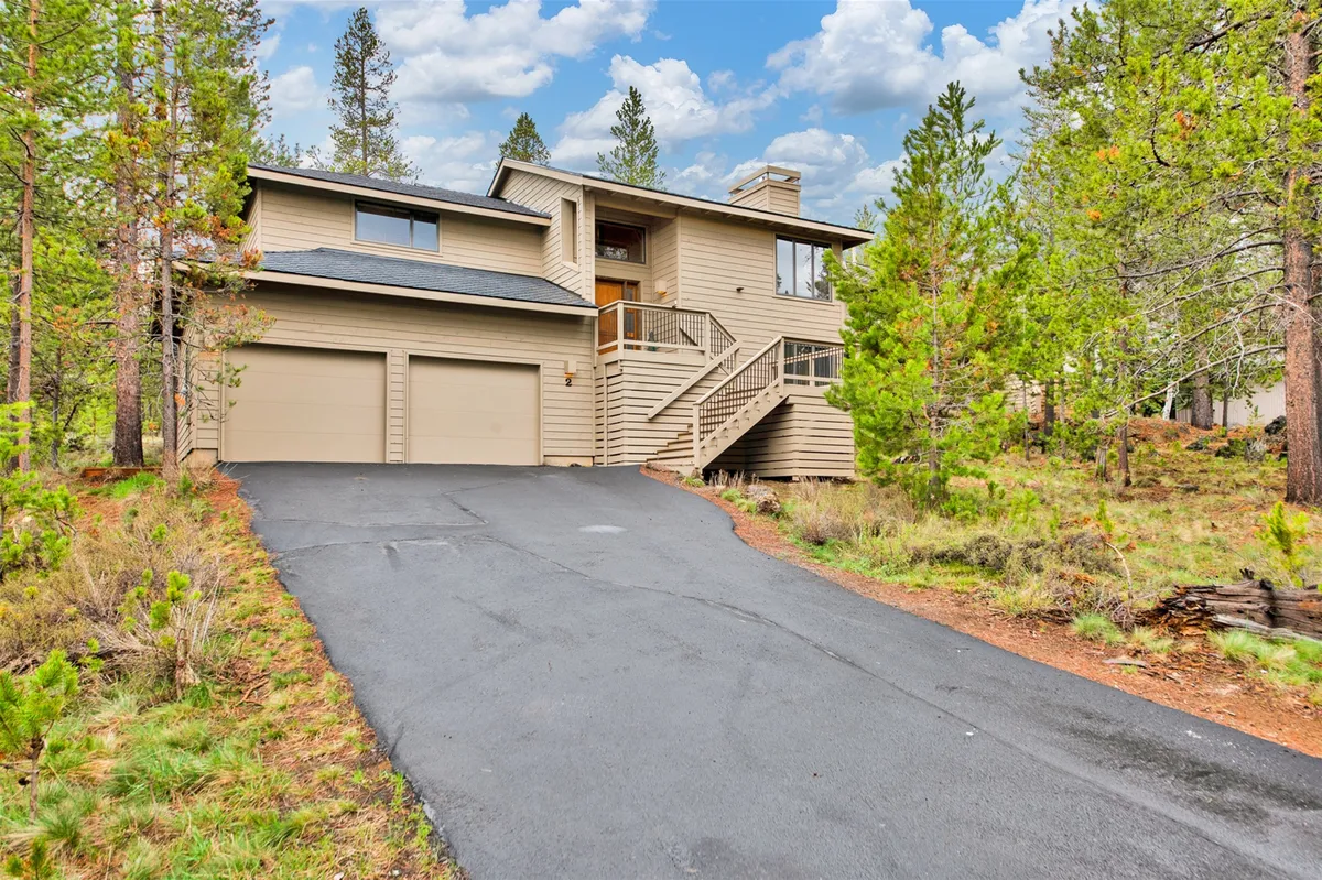 This image captures the home's facade nestled among tall trees, with the driveway leading up to the entrance. The natural setting hints at the property's connection to the outdoors, making it an ideal base for family adventures and exploration.