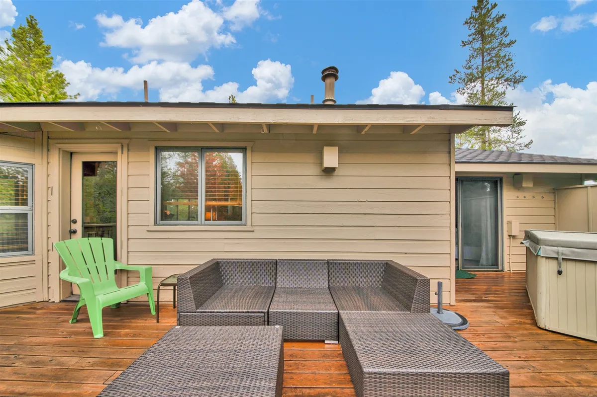The photo shows an inviting outdoor seating area on the deck, complete with a hot tub and a comfortable green chair. The setting encourages socializing, stargazing, and outdoor dining, making it ideal for summer BBQs or evening drinks.